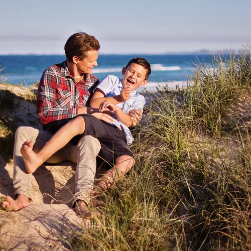 A father and son sharing a laugh among the coastal dunes